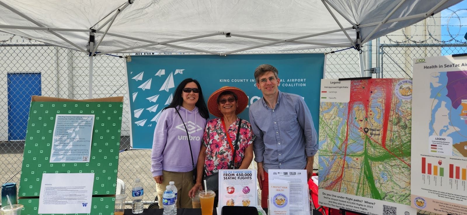 Drei Aktivist*innen des Kampfes gegen den King County International Airport, die auf einer lokalen Ressourcenmesse ausstellen